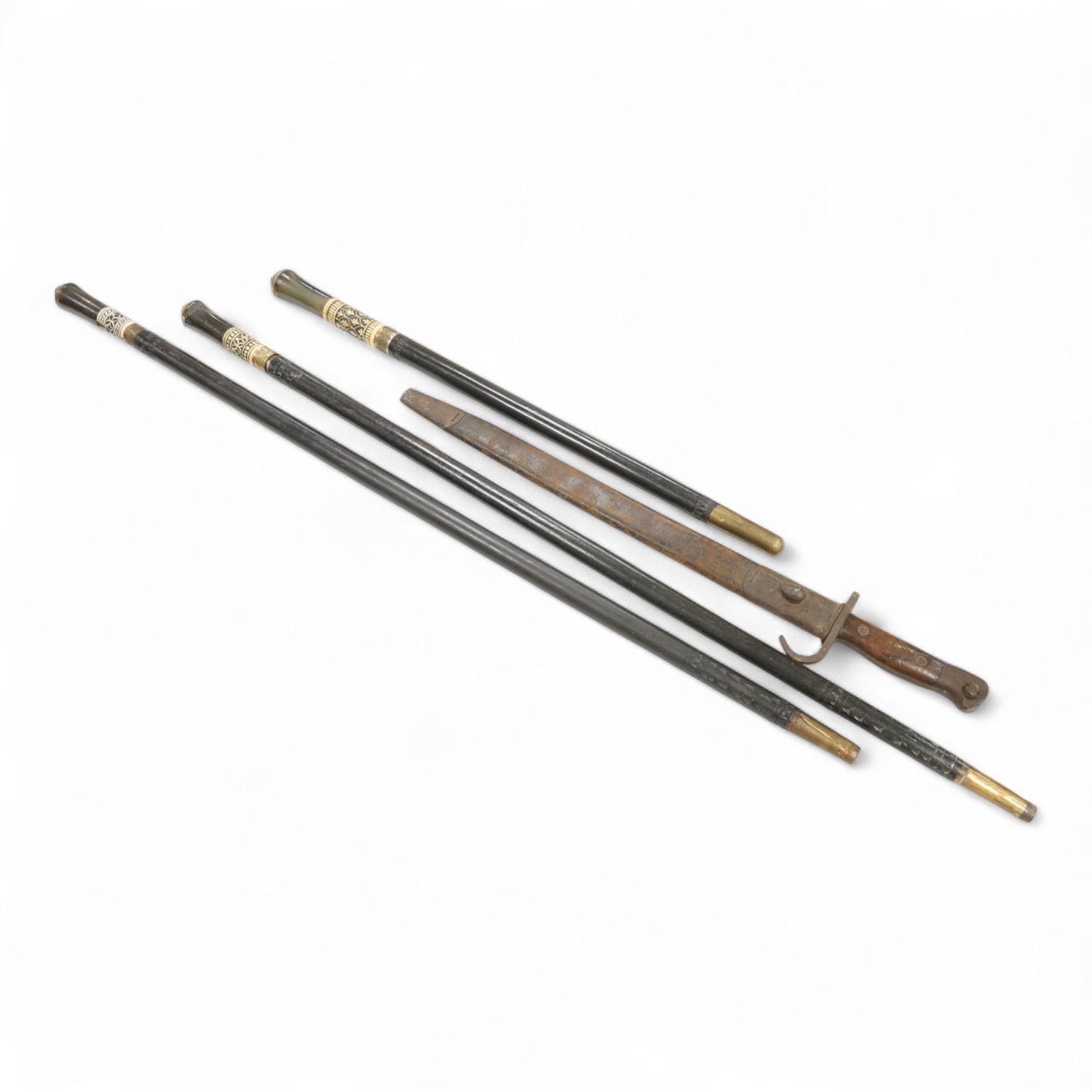 Three early 20th century Indonesian bone overlaid sword sticks and a bayonet, largest 92cm in length
